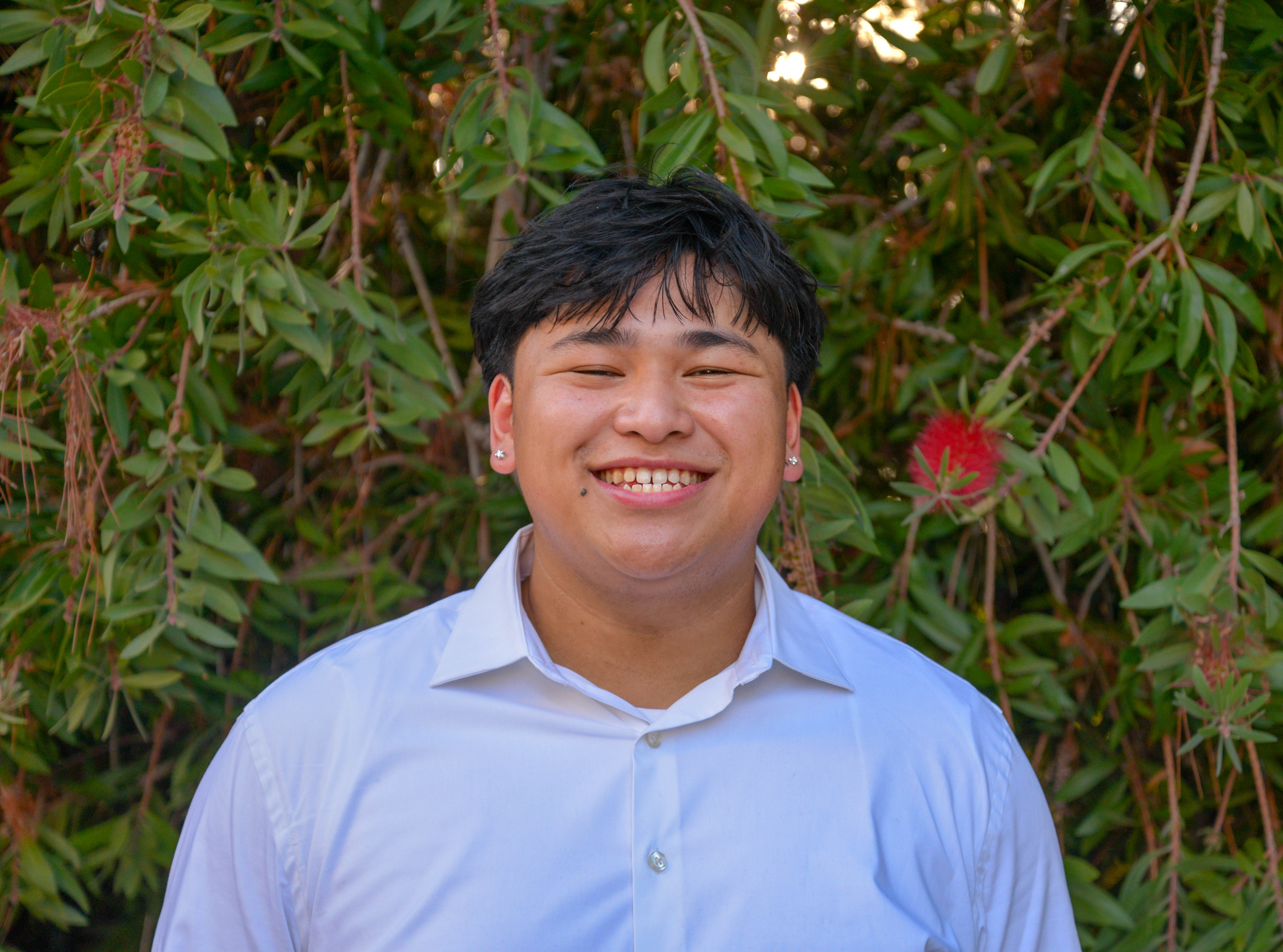 Jonathan Lau smiling in front of greenery